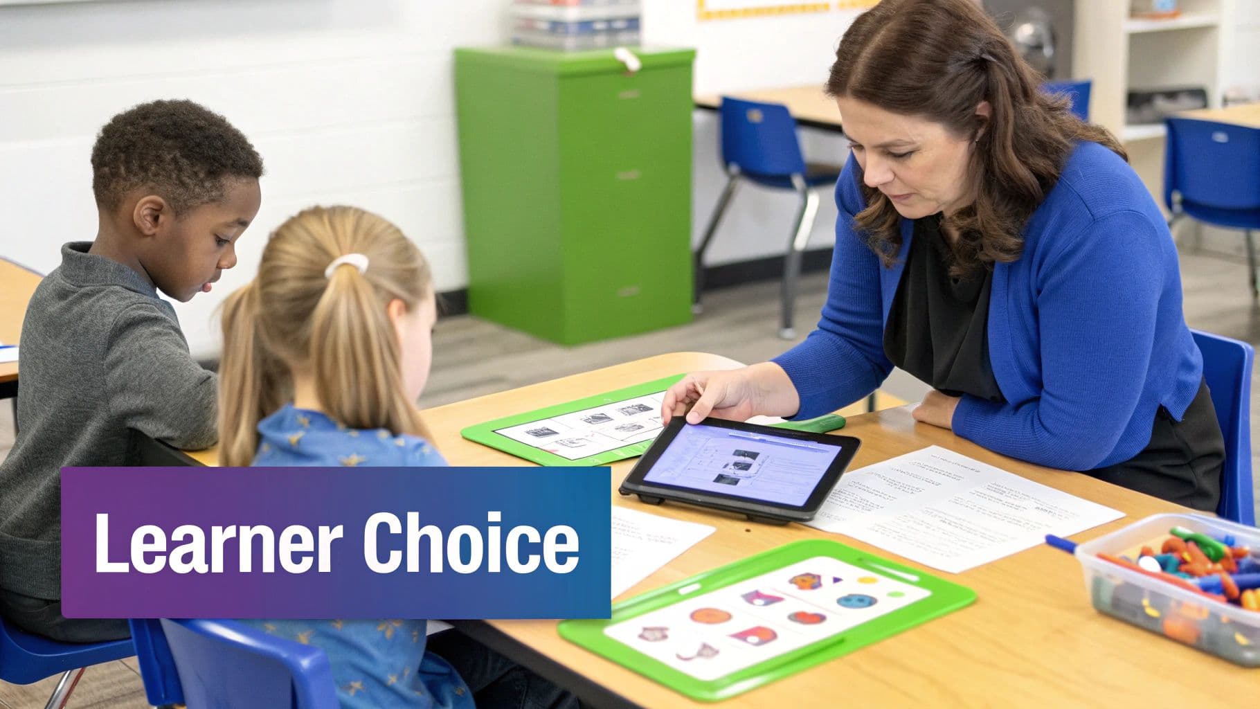 Teacher helps two young students with a tablet in a modern, collaborative classroom environment.